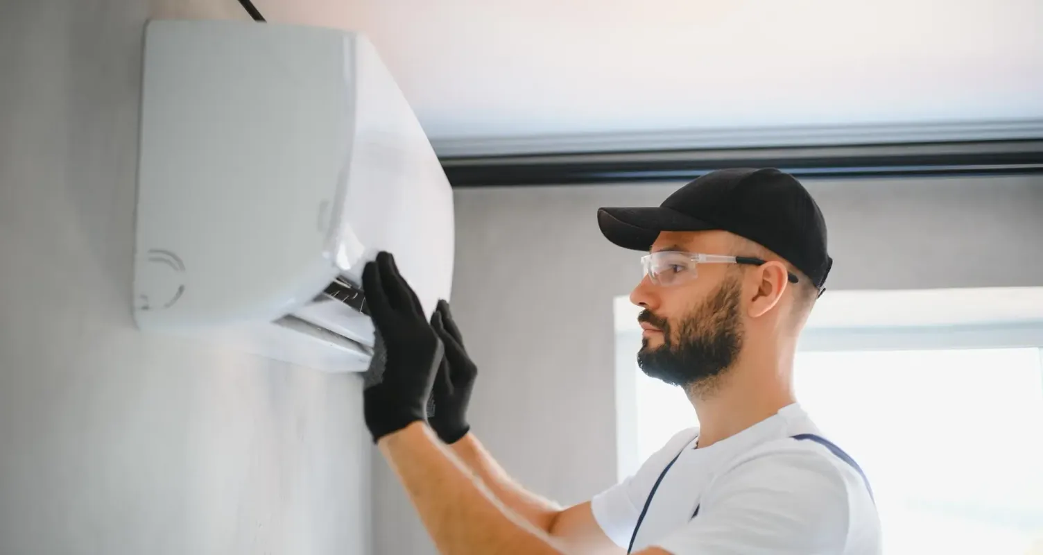 Installatore che fissa a parete lo split interno di un condizionatore.