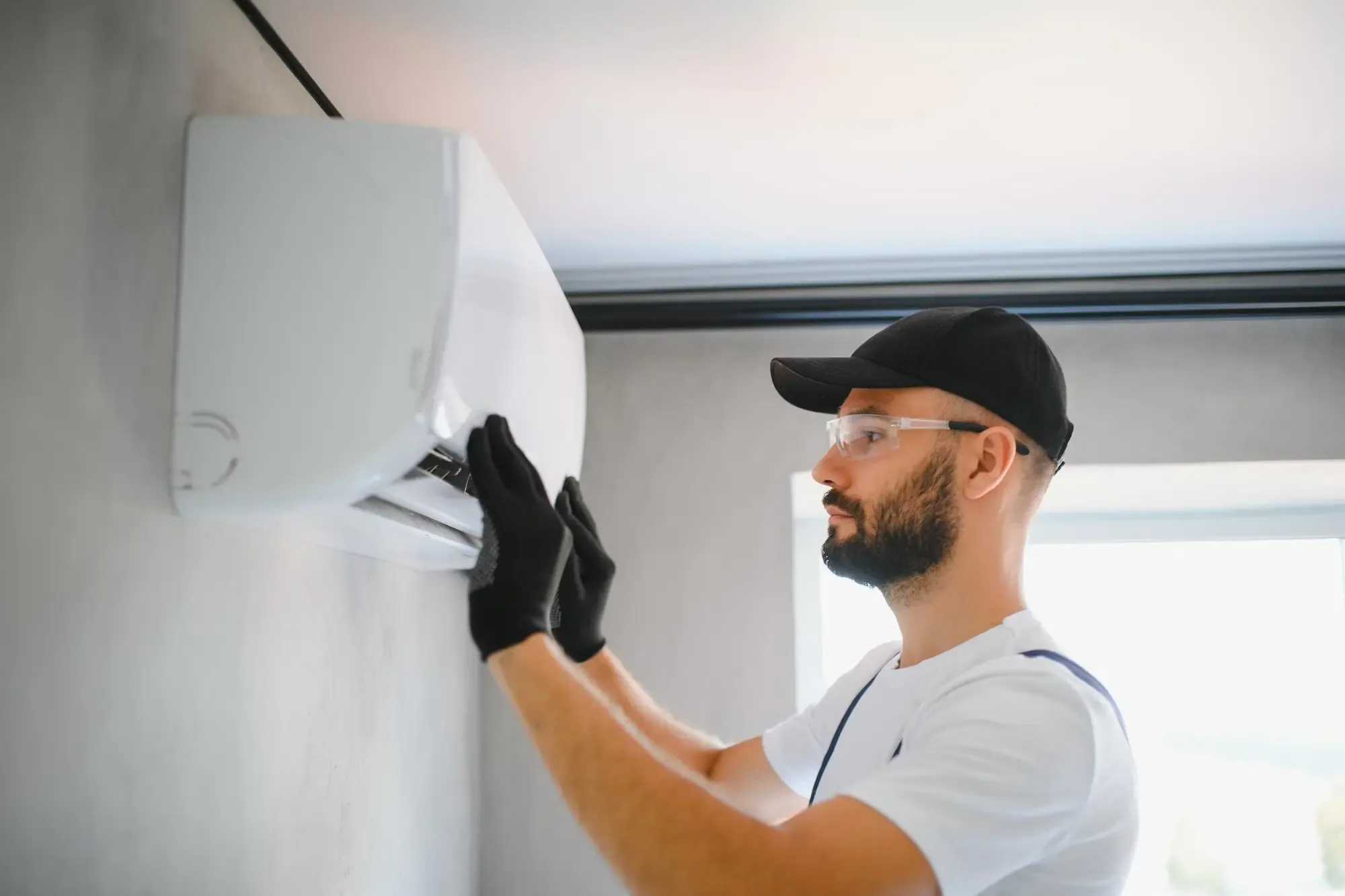 Installatore che fissa a parete lo split interno di un condizionatore.