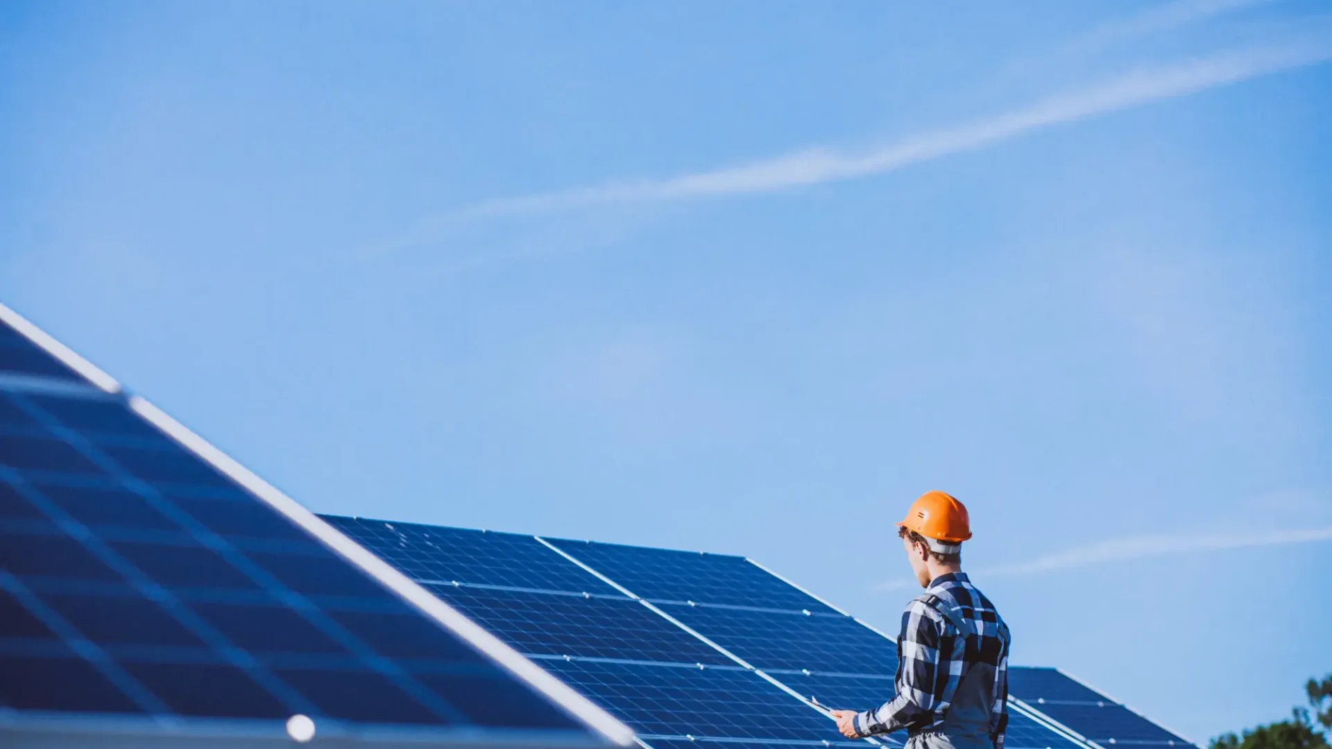 Installatore di Beni Energia che controlla una checklist di qualità davanti a un impianto fotovoltaico a terra.