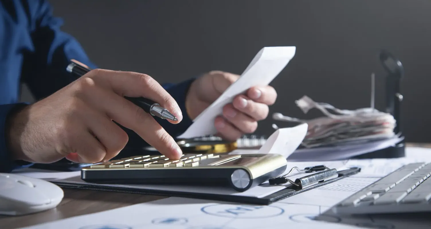 Calcolatrice e penna sopra a documenti, per rappresentare la pianificazione di un finanziamento.