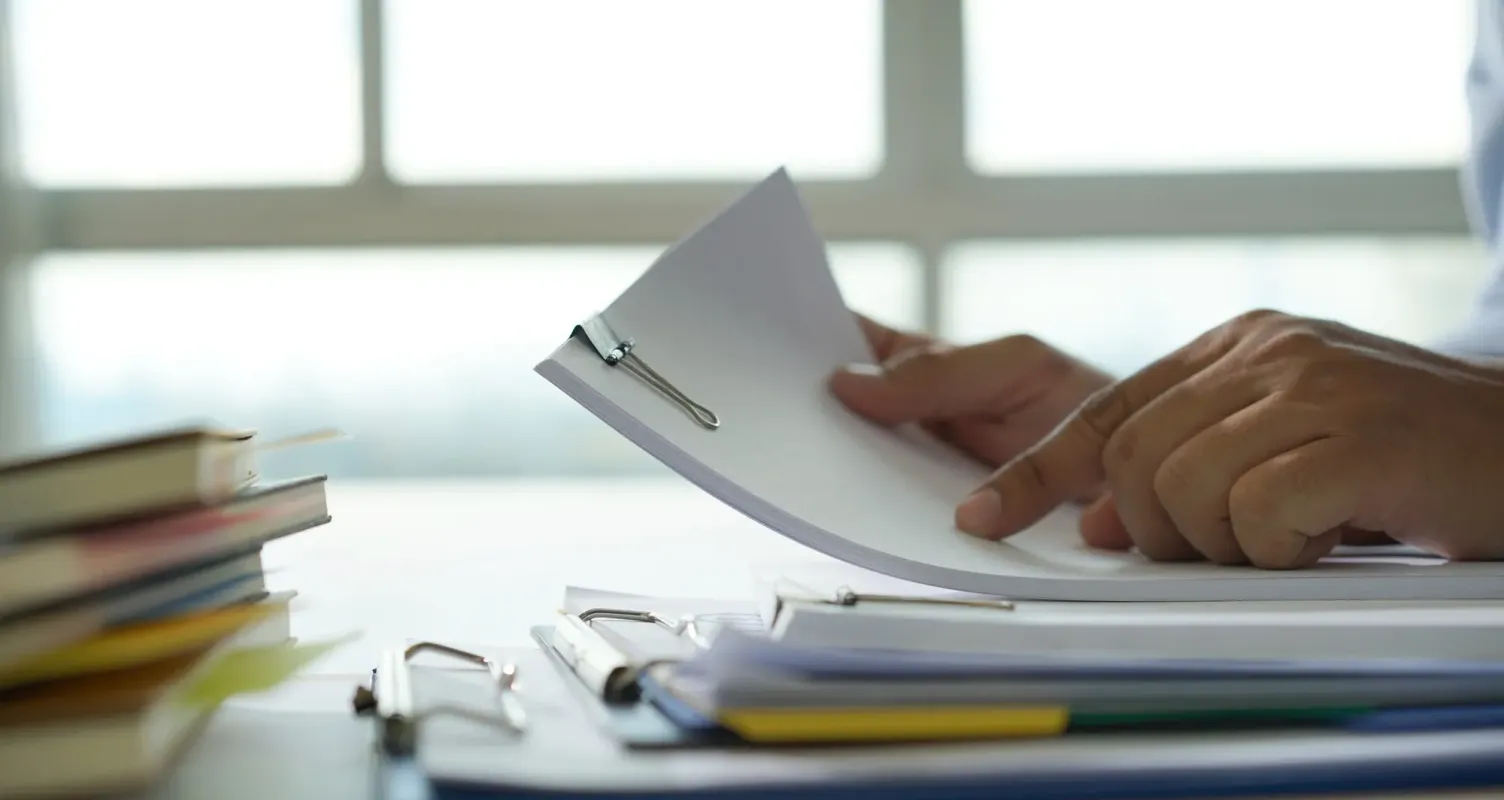 Persona che firma dei documenti, simboleggiando la gestione di pratiche burocratiche per incentivi.